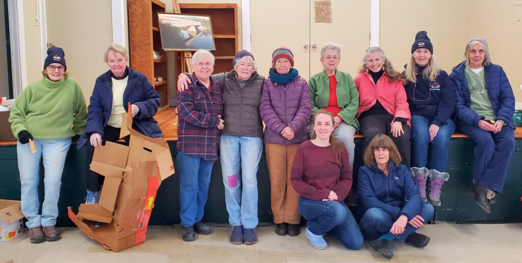 A group of a dozen people pose for a group photo inside a building