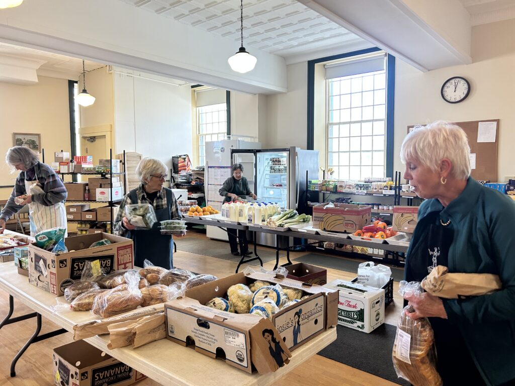 Lyme food pantry volunteers set our and arrange food on folding tables