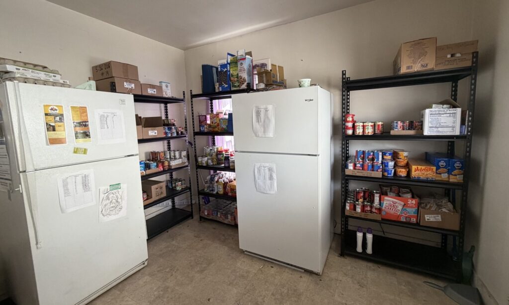 H2RC food pantry shelf The interior of a room, containing two fridges and several shelves of food.